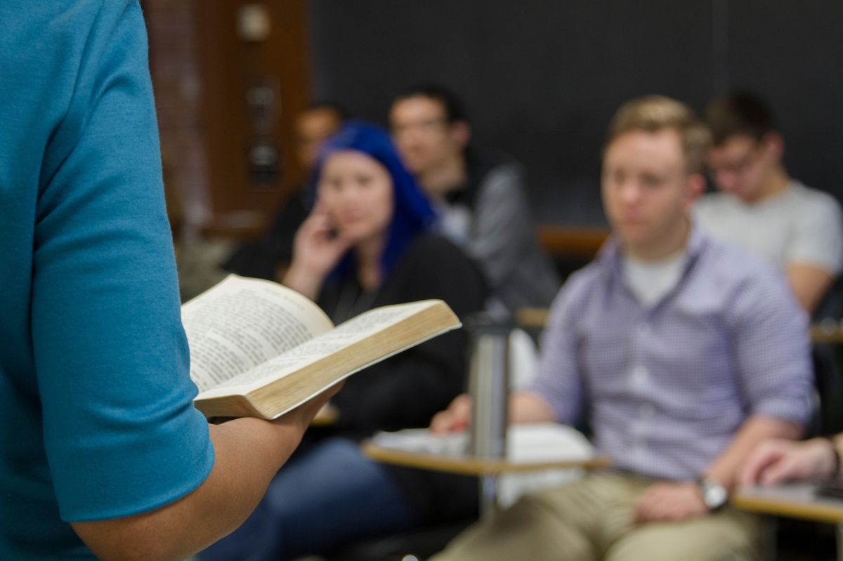 photo of a person reading from a book to a classroom of students